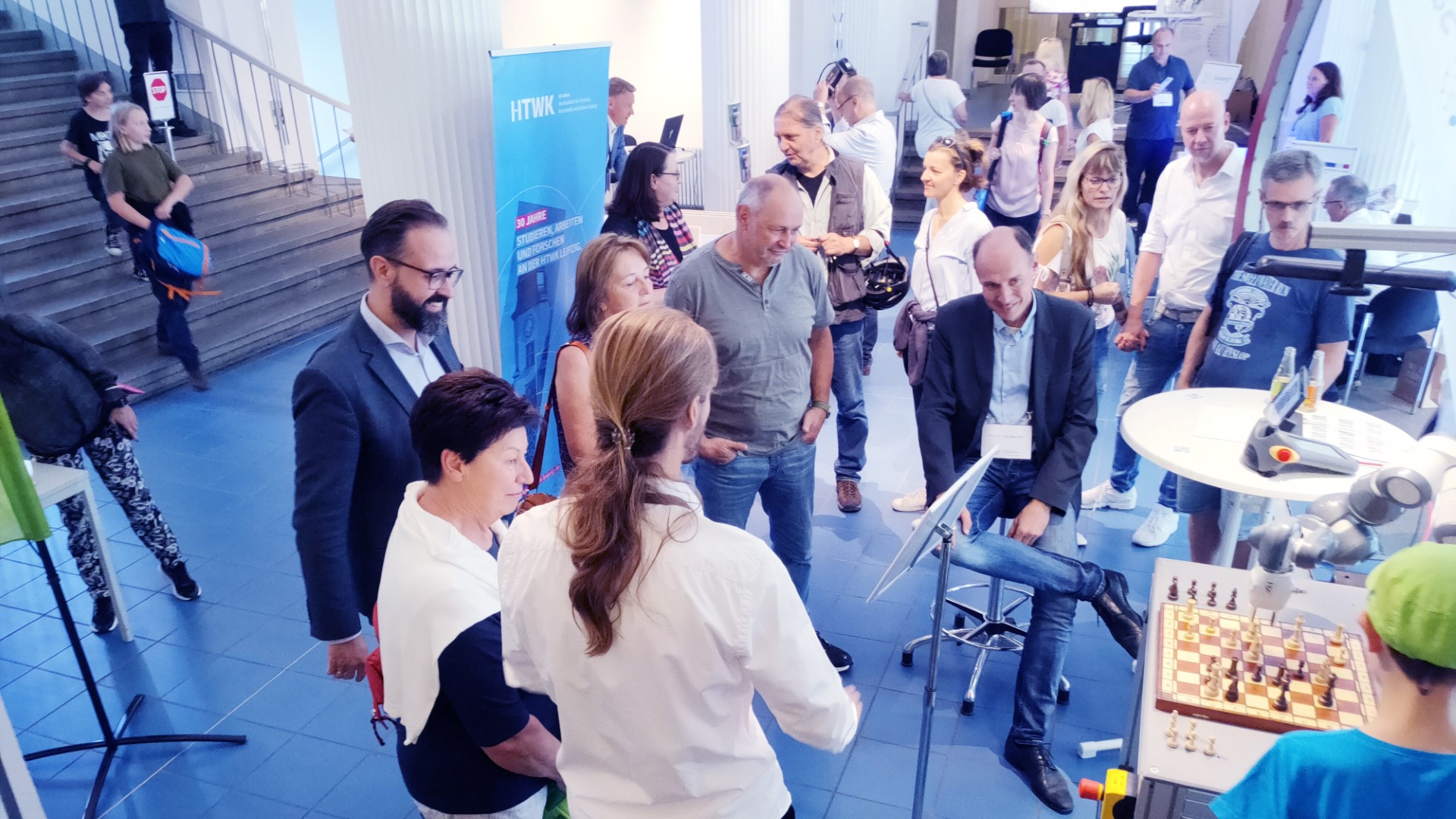Gruppe von Menschen schaut einem Roboter und einem Kind zu, die Schach spielen.