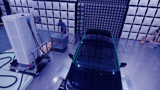 Blick auf Person, verschiedene Technische Geräte und ein Auto auf einem Versuchstand.