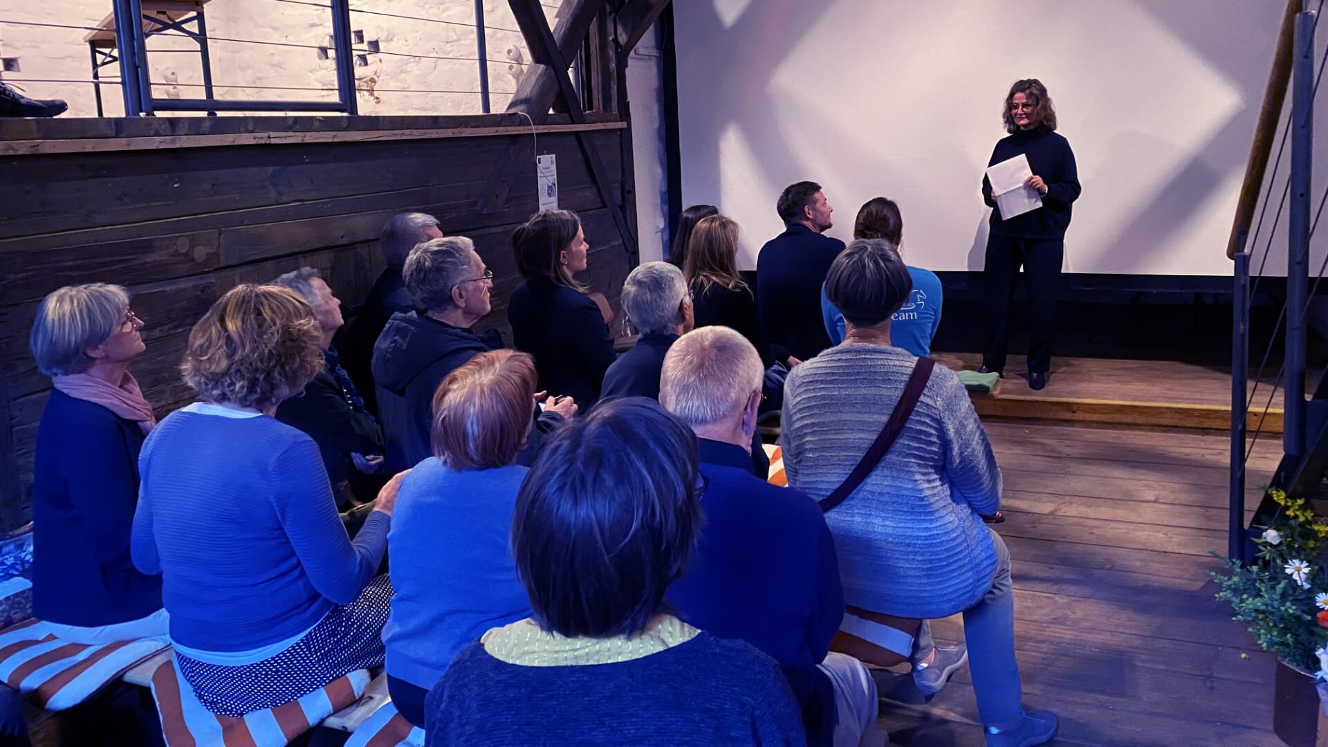 Person steht vor einer Leinwand und spricht zum Publikum.